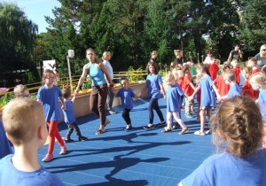 Dzieci tańczą w kole na tarasie przedszkolnym.