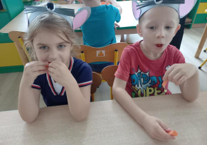 Dzieci jedzą marchewki.