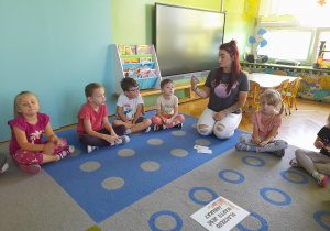 Nauczycielka czyta dzieciom informacje o jabłku.