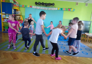 Dzieci tańczą w kółeczku z nauczycielką.