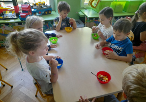 Dzieci jedzą sałatkę.