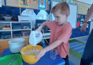 Chłopiec miksuje masło z cukrem i jajkami.