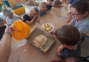 Nauczycielka przekłada masę ciasta do blaszki.
