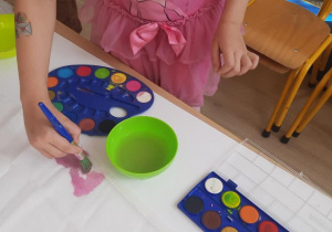 Dziecko maluje po gazie pędzlem namoczonym w farbie.