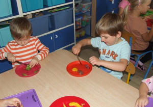 Dzieci kroją owoce na sałatkę.