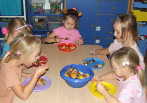 Dzieci jedzą sałatkę owocową.