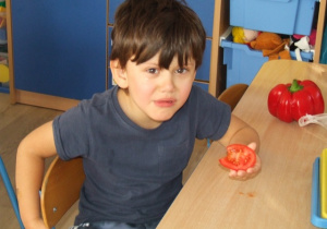 Chłopiec je plaster pomidora.