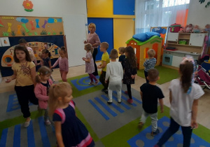 Dzieci spacerują po sali z szablonem monety w ręku.