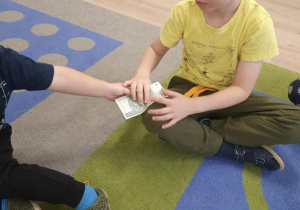 Dzieci ogladają banknot.