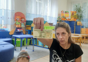 Nauczycielka pokazuje stary banknot - 50 złotych.