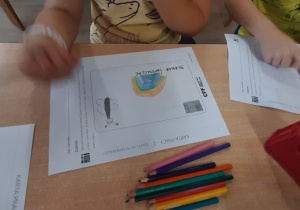 Dzieci przy stolikach projektują kartę do banlomatu.