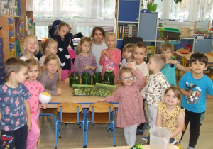 Dzieci prezentują gotowe przetwory w słoikach i foliach.