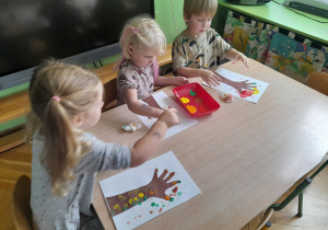 Dzieci malują kolorowe kropki używając swoich palców.