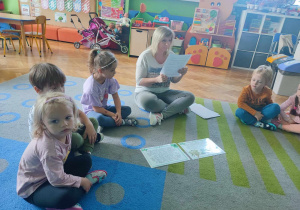 Dzieci słuchają informacji, czytanych przez nauczycielkę.