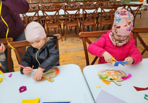 Dzieci ozdabiają sylwety dyni na warsztatach plastycznych.