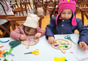 Dzieci ozdabiają sylwety dyni na warsztatach plastycznych.