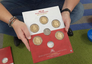 Nauczycielka pokazuje dzieciom kolekcjonerskie monety.