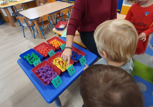Nauczycielka wspólnie z dziećmi odczytuje ceny produktów.
