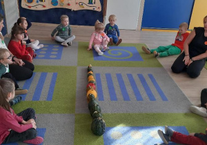 Dzieci ogladają ułożone dynie na dywanie.