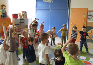 Dzieci wykonują ćwiczenia gimnastyczne zgodnie z piosenką.