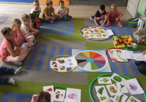Dzieci oglądają posegregowane owoce i warzywa.