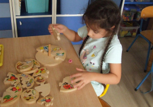 Dziewczynka układa piramidę żywienia z drewnianych klocków.