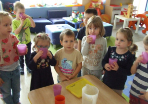Dzieci piją koktajl owocowy.