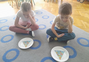 Dzieci oglądają talerzyk z piramidą zdrowego żywienia.