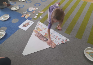 Dziewczynka uklada ilustrację na piramidzie.
