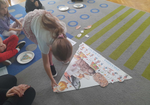 Dziewczynka uklada ilustrację na piramidzie.