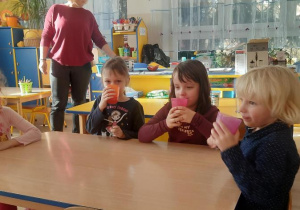 Dzieci piją koktajl truskawkowy.