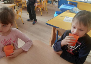 Dzieci piją koktajl truskawkowy.