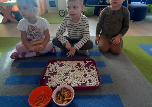 Dzieci przed przebranym makaronem i grochem.