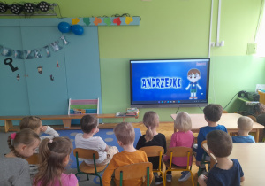 Dzieci oglądają film edukacyjny o andrzejkach.