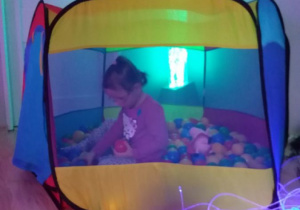 Dziewczynka bawi się w namiocie z piłkami.