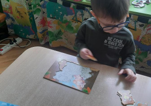 Chłopiec układa misiowe puzzle.