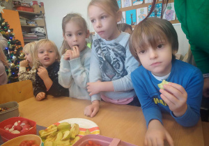 Dzieci jedzą owoce i warzywa.