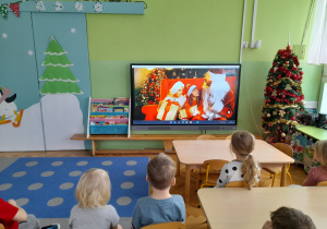 Dzieci oglądają film edukacyjny o Św. Mikołaju.