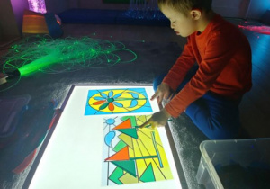 Chłopiec układa obrazek z kolorowych figur.