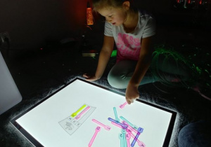 Dziewczynka układa łyżeczki z literami wg wzoru.