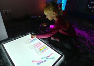 Dziewczynka układa wyrazy wykorzystując łyżeczki z literami.