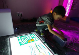 Chłopiec układa mozaikę z kolorowych figur.