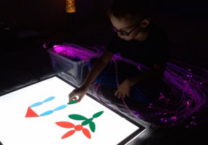 Chłopiec układa obrazek wykorzystując kolorowe figury.