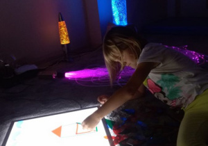 Dziewczynka układa obrazek z kolorowych figur.