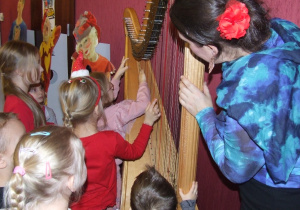 Dzieci próbują gry na harfie.