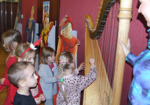 Dzieci próbują gry na harfie.