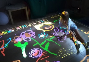 Dziewczynka rysuje na podłodze interaktywnej.