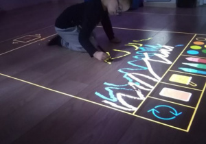 Chłopiec rysuje na podłodze interaktywnej.