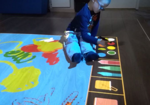 Chłopiec koloruje na podłodze interaktywnej.