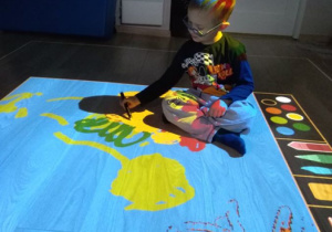 Chłopiec koloruje obrazek na podłodze interaktywnej.